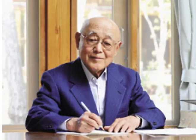 Mr. Maki writing at a desk in a blue suit